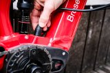 Eine Person schließt ein Ladekabel am Rahmen eines E-Bikes an.